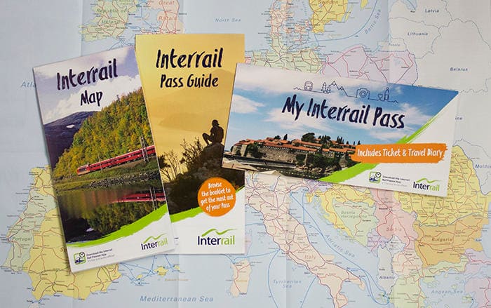 Image of the Interrail Travel Pack including an Interrail Pass Guide, Pass Cover, and Map laid on a map of Europe.